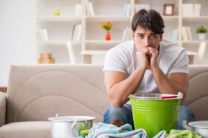 a man sitting on the couch in front of a ceiling leak