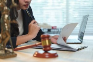 Attorney reviewing legal documents at a desk with a laptop, gavel, and Lady Justice statue
