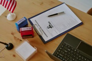 Immigration application on a clipboard beside approval and rejection stamps, a laptop, and a small American flag